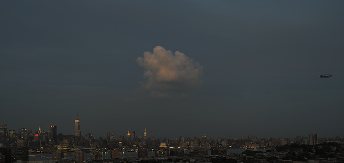 dusk view of new york city showing a lone cloud illuminated by a setting sun