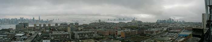 fog rolls up the hudson under gray cloudy sky. sun glowing thru in several areas